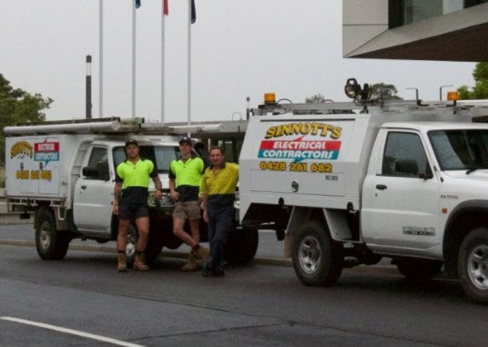 Sinnott Electrical staff with two signwritten work utes